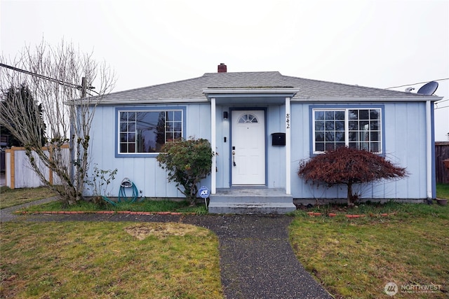 bungalow-style house with a front yard and roof with shingles