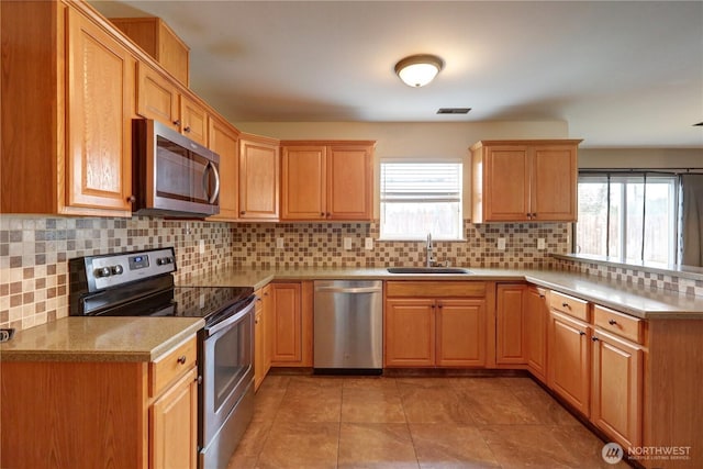 kitchen with light tile patterned flooring, stainless steel appliances, backsplash, and sink