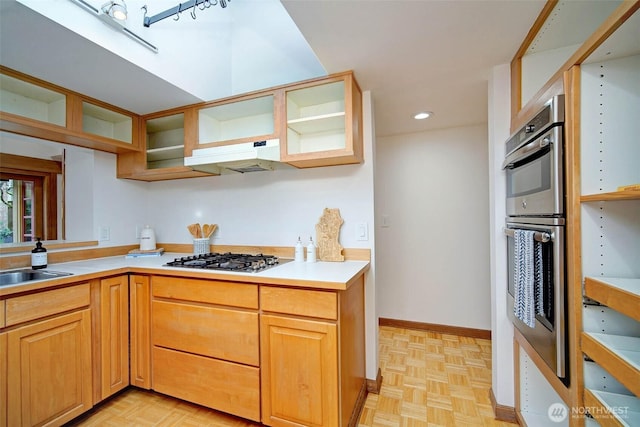 kitchen with light countertops, under cabinet range hood, double oven, gas cooktop, and a sink