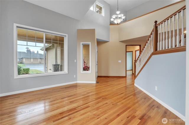 interior space with a wealth of natural light, a notable chandelier, stairway, and light wood finished floors