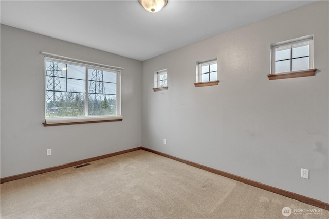 unfurnished room featuring baseboards, visible vents, and light colored carpet