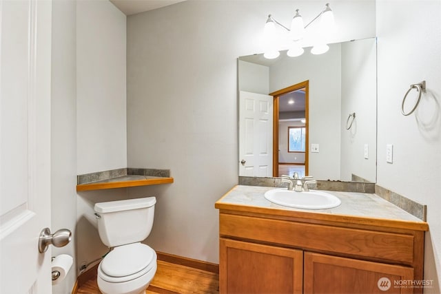 bathroom featuring toilet, wood finished floors, vanity, and baseboards