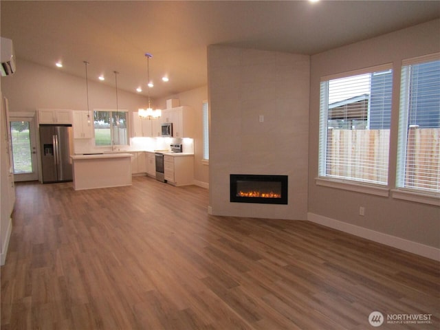 unfurnished living room featuring a notable chandelier, a tile fireplace, vaulted ceiling, and dark wood-type flooring