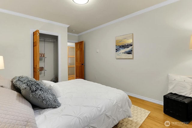 bedroom featuring light wood-style floors, baseboards, ornamental molding, and a closet