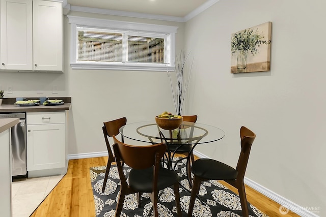 dining room with light wood-style floors, ornamental molding, and baseboards