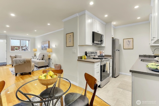 kitchen with ornamental molding, appliances with stainless steel finishes, a sink, and white cabinets