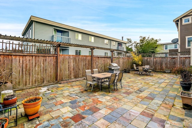 view of patio with outdoor dining space, a fenced backyard, and a grill