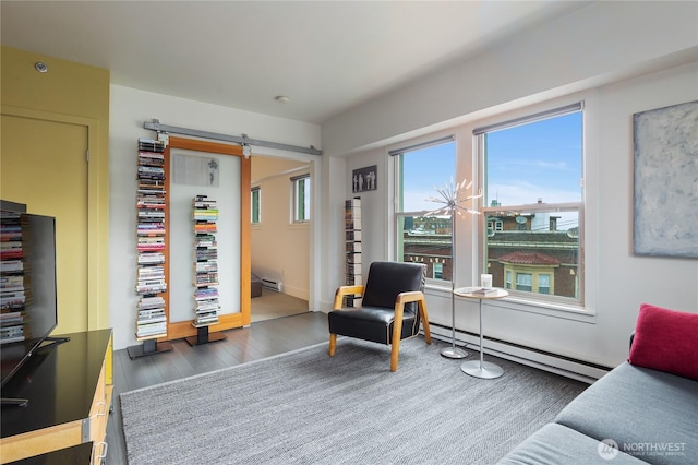 sitting room with dark wood-style floors, a baseboard radiator, a baseboard heating unit, and a barn door