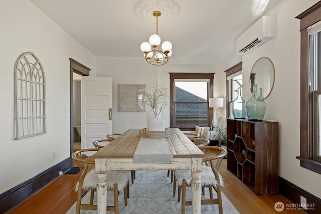 dining space with a wall mounted air conditioner, a chandelier, and light hardwood / wood-style flooring