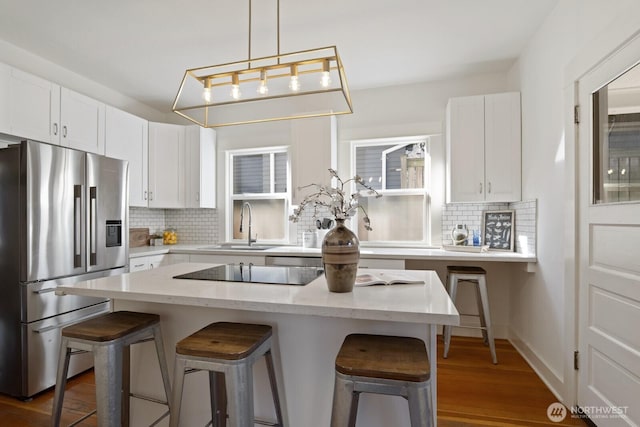 kitchen with sink, stainless steel fridge with ice dispenser, a breakfast bar, and white cabinets