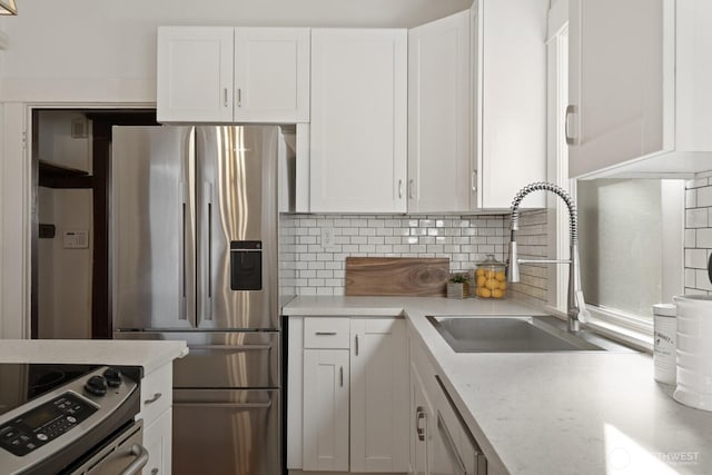 kitchen with decorative backsplash, sink, stainless steel appliances, and white cabinets