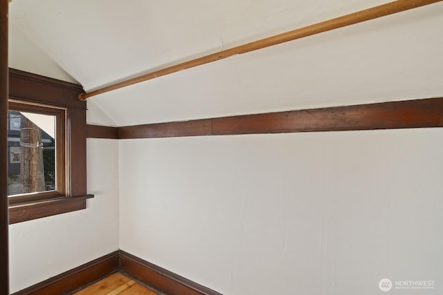 empty room featuring vaulted ceiling with beams and wood-type flooring