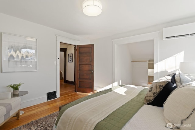 bedroom featuring hardwood / wood-style flooring and a wall unit AC