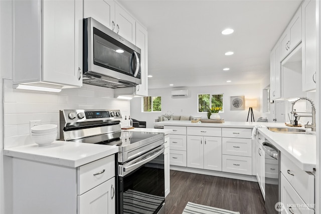 kitchen with appliances with stainless steel finishes, sink, kitchen peninsula, and white cabinets