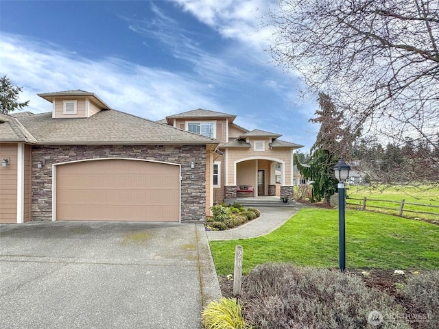 view of front of home with a front yard, fence, driveway, stone siding, and a garage