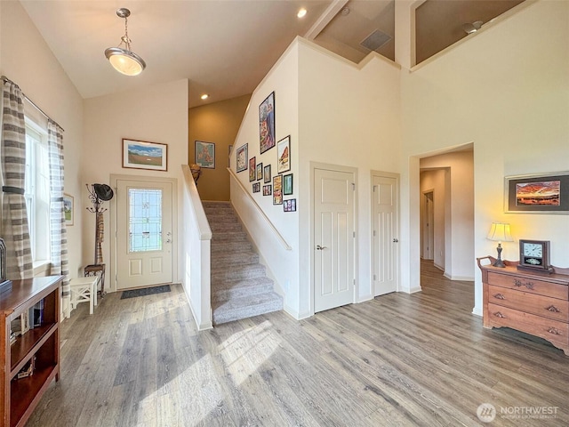 foyer featuring stairway, baseboards, high vaulted ceiling, and wood finished floors