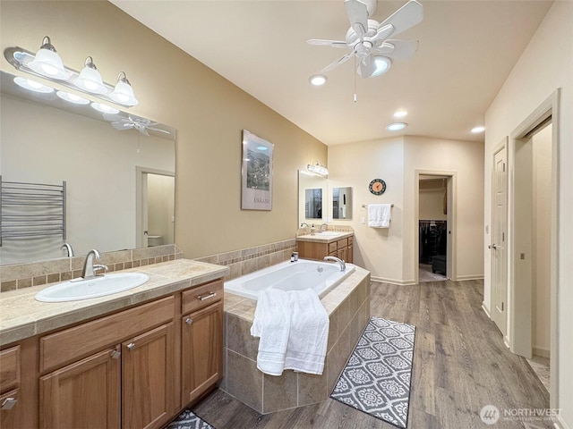 full bath featuring a bath, wood finished floors, ceiling fan, and a sink