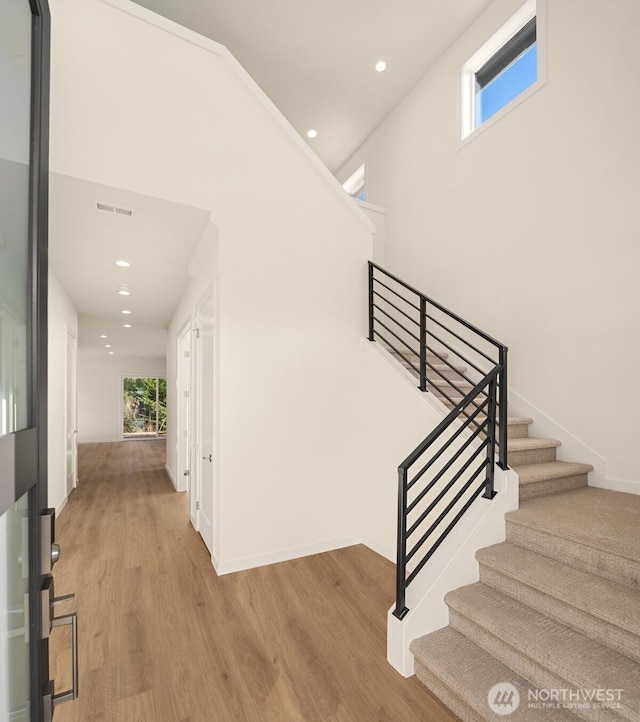 interior space with a high ceiling, baseboards, wood finished floors, and recessed lighting