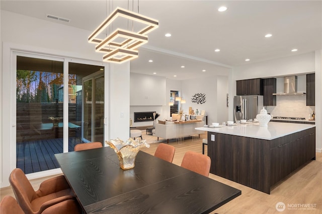 dining space featuring light wood-style floors, a lit fireplace, visible vents, and recessed lighting