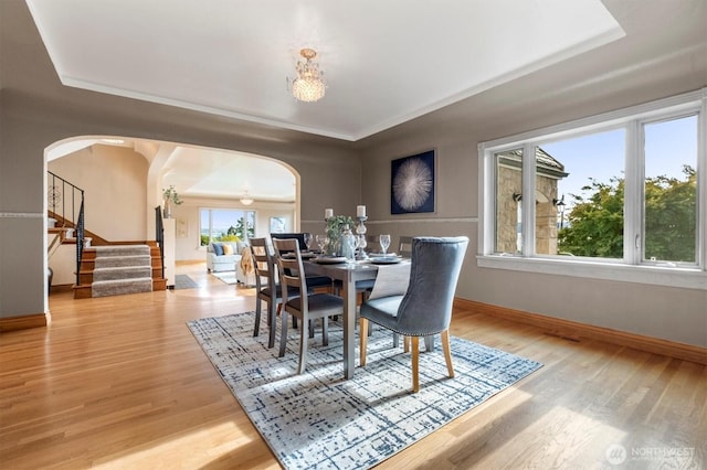 4801 Hyada Blvd NE, Tacoma, WA 98422 - dining room featuring a raised ceiling, arched walkways, wood finished floors, and stairs