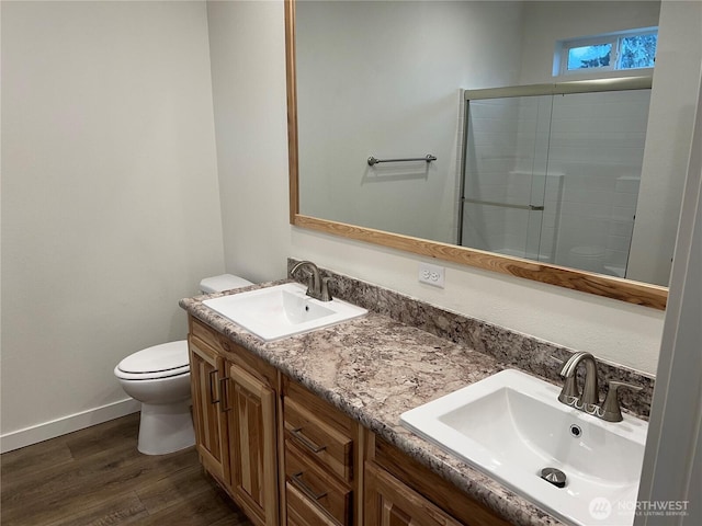 bathroom featuring hardwood / wood-style flooring, vanity, toilet, and a shower with door