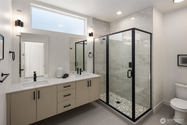 bathroom featuring toilet, vanity, tile patterned flooring, and a shower with shower door