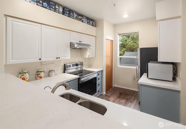 kitchen with white cabinets, stainless steel electric range, light countertops, under cabinet range hood, and a sink