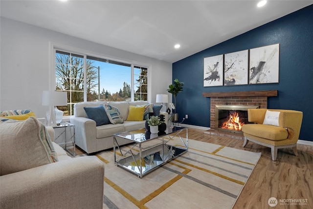 living room with hardwood / wood-style floors, vaulted ceiling, and a fireplace