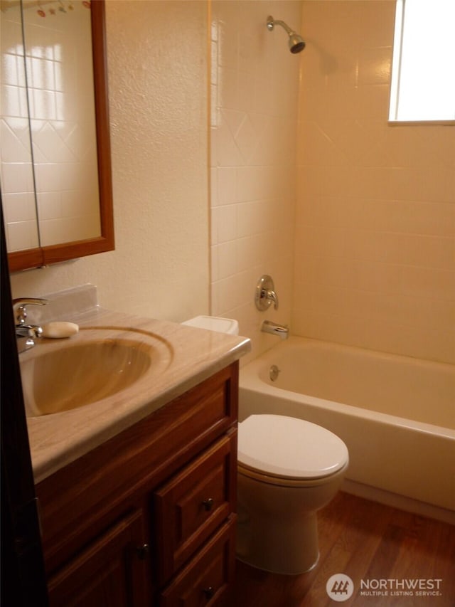 full bathroom with tiled shower / bath combo, vanity, wood-type flooring, and toilet