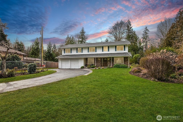 traditional-style home featuring a garage, driveway, fence, and a lawn