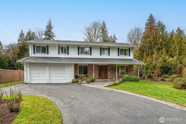 traditional home with aphalt driveway, an attached garage, fence, a front yard, and brick siding