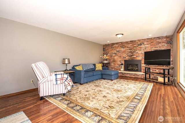 living room featuring a brick fireplace, dark wood finished floors, and baseboards