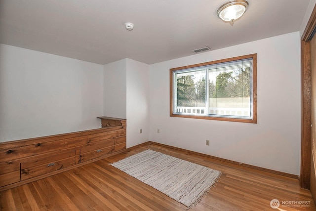 spare room with light wood-style floors, baseboards, and visible vents