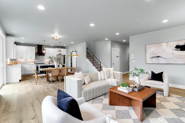 living area featuring recessed lighting, baseboards, light wood finished floors, and stairs