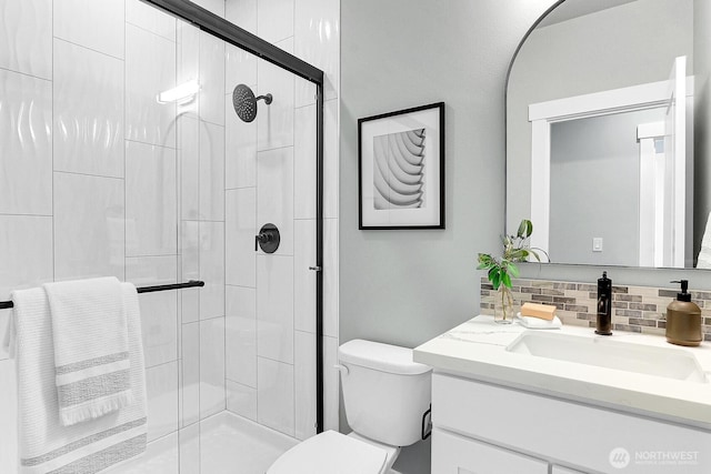 bathroom with toilet, a stall shower, tasteful backsplash, and vanity