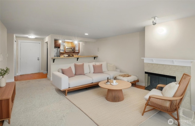 living room featuring recessed lighting, a tile fireplace, and baseboards