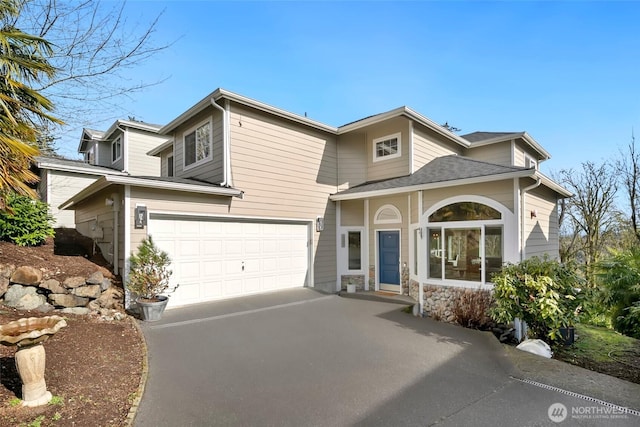 view of front of property with driveway, stone siding, and a garage