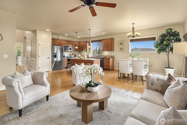 living room featuring ceiling fan with notable chandelier and light hardwood / wood-style floors