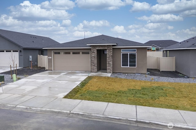 view of front facade with stucco siding, an attached garage, a front yard, fence, and driveway