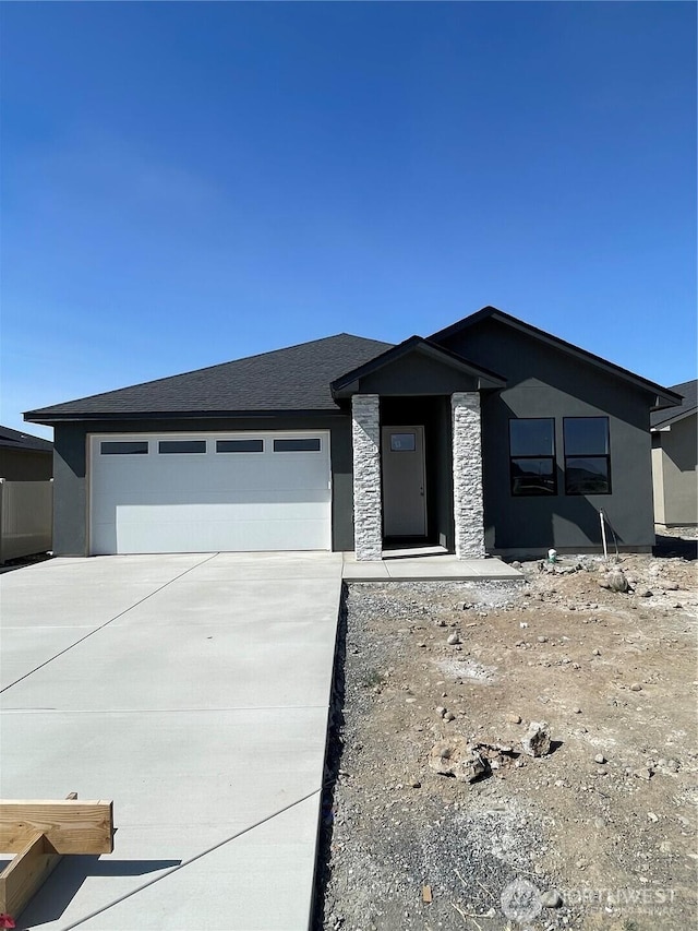 1117 9th Ave NE, Ephrata, WA 98823 - view of front facade featuring driveway, an attached garage, and stone siding
