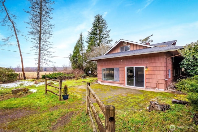 back of house with a rural view and a lawn