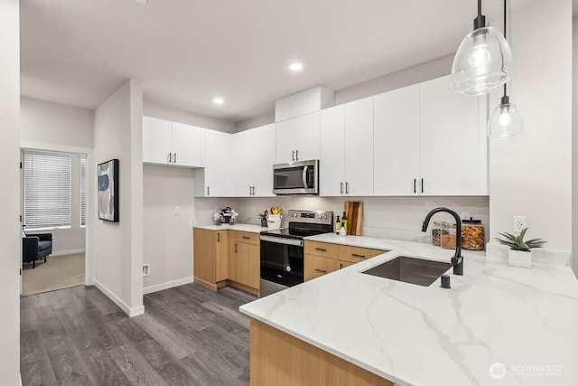 kitchen with hanging light fixtures, sink, light stone counters, appliances with stainless steel finishes, and white cabinets