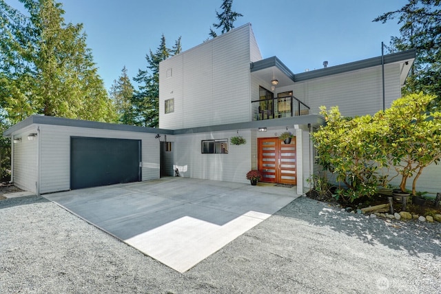 view of side of home with a garage, concrete driveway, and a balcony