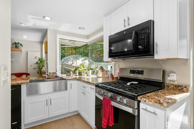 kitchen with stainless steel range with gas cooktop, black microwave, white cabinetry, and a sink