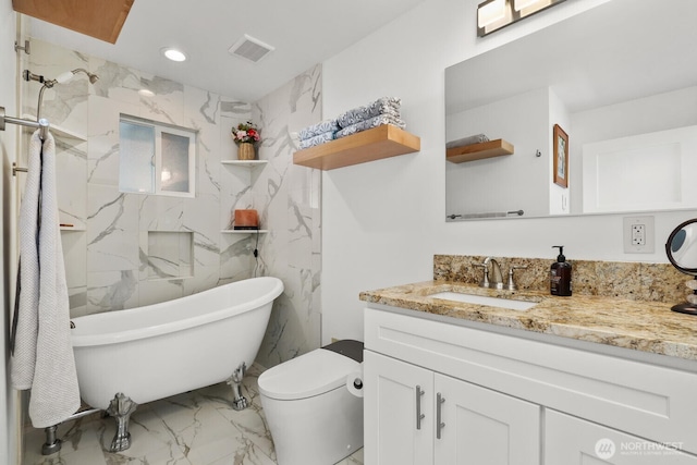 full bath featuring toilet, marble finish floor, a freestanding bath, vanity, and recessed lighting