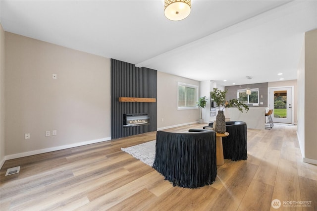 living area with light wood finished floors, a fireplace, visible vents, and baseboards