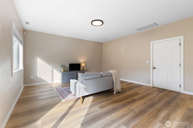 living area with wood finished floors, visible vents, and baseboards