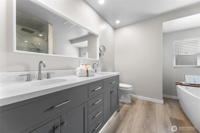 full bath with a stall shower, a sink, a freestanding bath, and wood finished floors