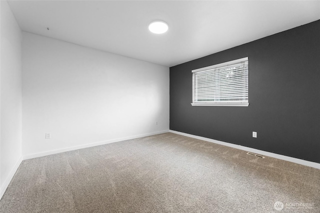 carpeted empty room with visible vents and baseboards