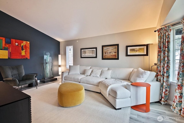 living area featuring light wood-style floors, lofted ceiling, and baseboards